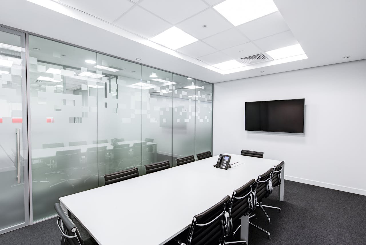 Sleek, minimalist conference room with glass walls, long table, and office chairs.